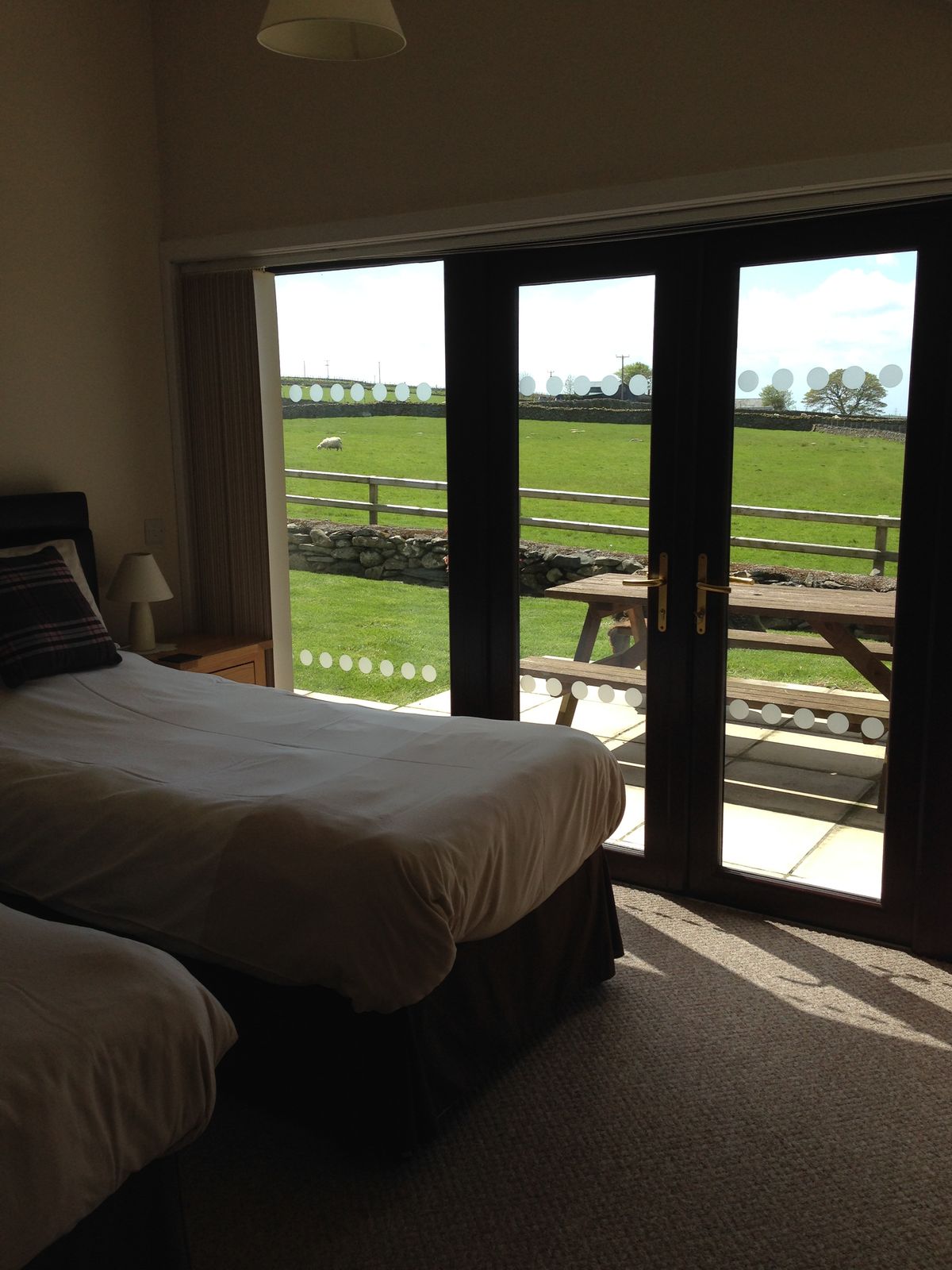 Ground-floor twin bedroom with patio doors opening onto the garden and fields beyond