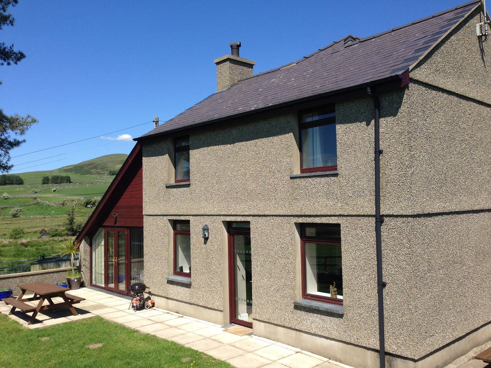 Bryn-Weirglodd farmhouse seen from the garden, with a picnic table and barbecue on the patio